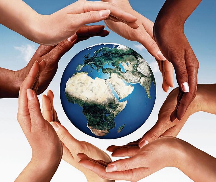 Symbol für Frieden und kulturelle Vielfalt: multiethnische Hände, die auf blauem Himmelshintergrund einen Kreis um die Welt herum bilden.